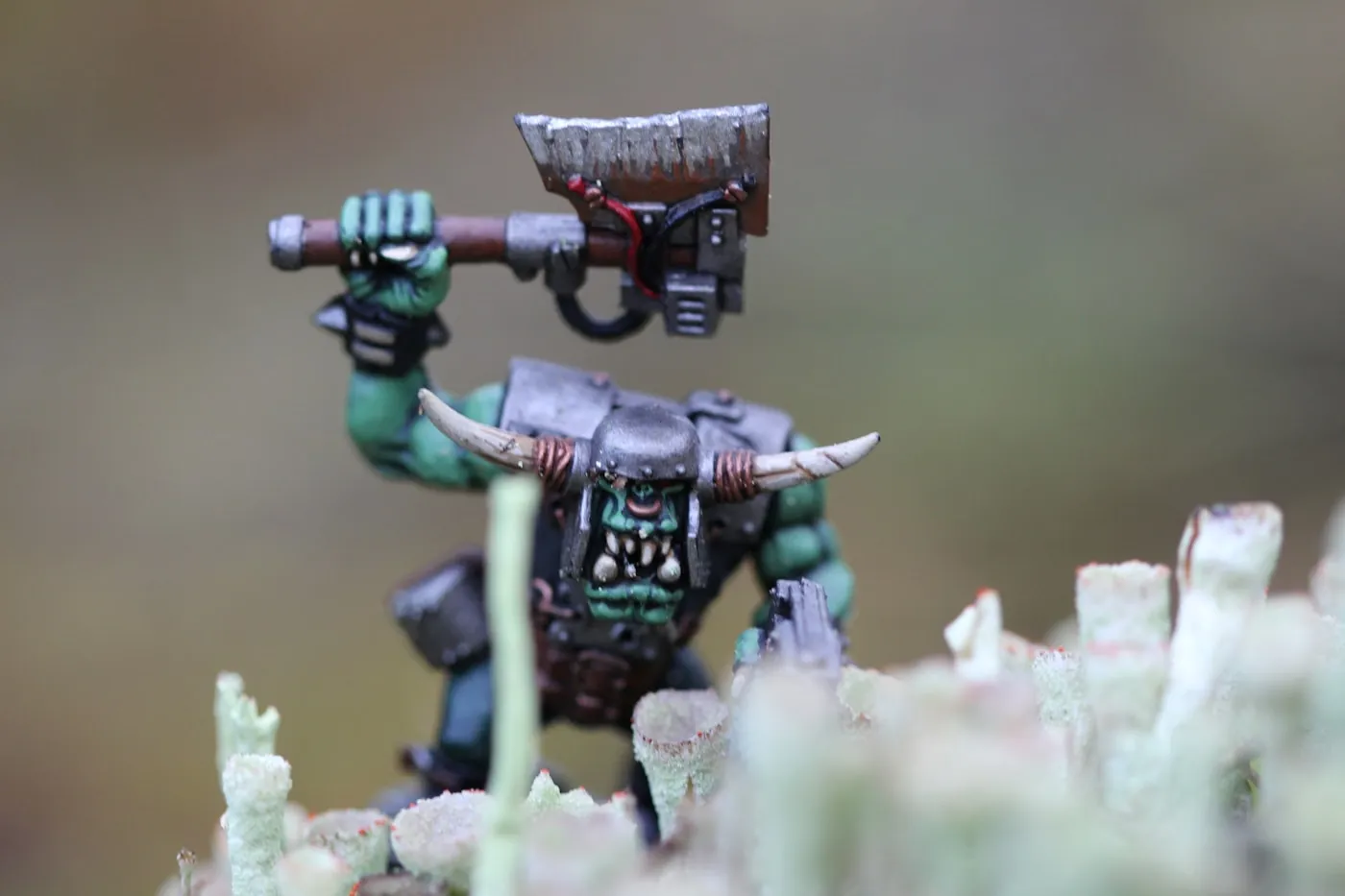 Green-skinned ork miniature raising a jagged cleaver, painted with freehand detail and dirt-toned base.